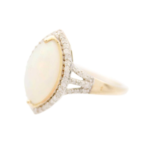 130 - A 9ct white opal and diamond set dress ring. The marquise shaped cabochon opal displaying multiple c... 