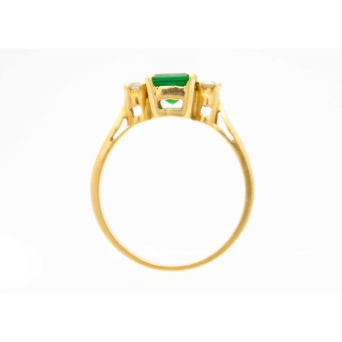 148 - An 18ct synthetic emerald and diamond set three-stone ring. The emerald of 1.30ct estimated weight, ... 