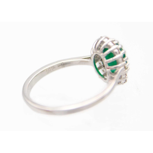 149 - An 18ct white gold oval emerald and diamond set cluster ring. The emerald of 1.30ct estimated weight... 