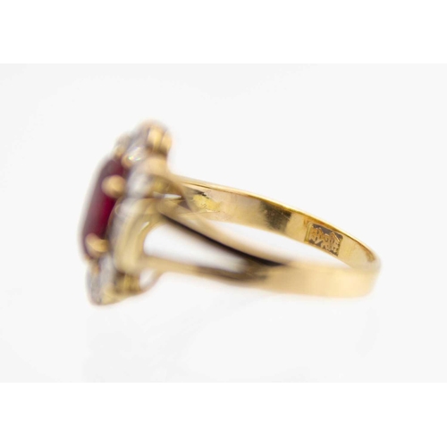 180 - A modern Chinese 18ct ruby and diamond cluster ring. The oval cut ruby of 0.85ct estimated weight, s... 