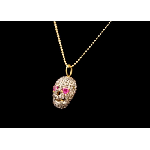 203 - A skull pendant set with diamonds and ruby eyes. Set in silver gilt, the ruby eyes of 0.20ct total e... 