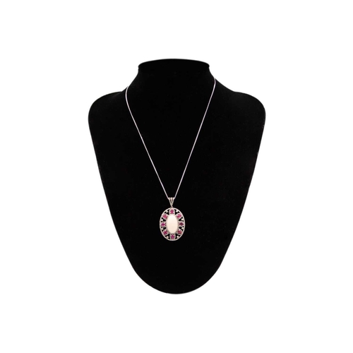 207 - A large oval cabochon coral, diamond and ruby set pendant. Set in white metal, the central coral mea... 