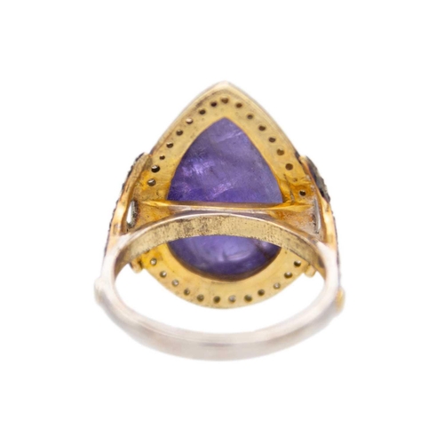 223 - A pear shaped cabochon tanzanite and diamond set dress ring. Set in silver gilt, the tanzanite of 10... 