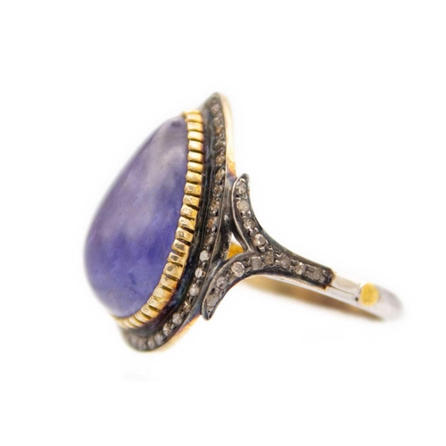 223 - A pear shaped cabochon tanzanite and diamond set dress ring. Set in silver gilt, the tanzanite of 10... 