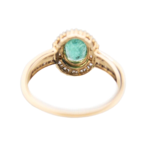 256 - A 9ct emerald and diamond set dress ring. The oval cut emerald of 1.02ct estimated weight, surrounde... 