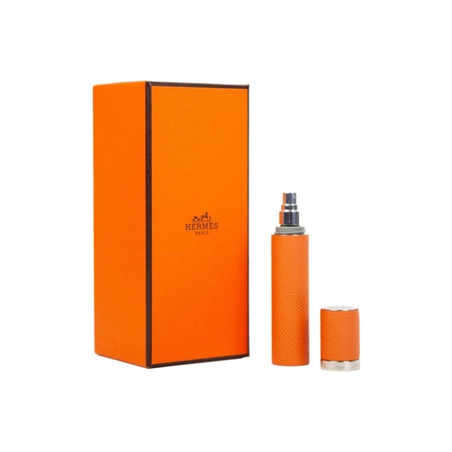 320 - HERMES - An unused orange leather-cased glass refillable perfume atomizer. Within original canvas po... 