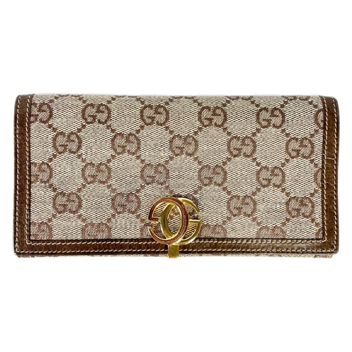 322 - GUCCI - A wallet in embroidered GG fabric and brown leather trim. In original cardboard box; width 1... 