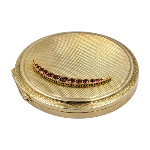 55 - A modern silver gilt compact applied with a 9ct garnet and diamond crescent. The engine turned compa... 