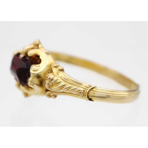 83 - A Victorian high-purity gold (tests 14ct) bangle with large red paste stone. Of hollow scroll emboss... 