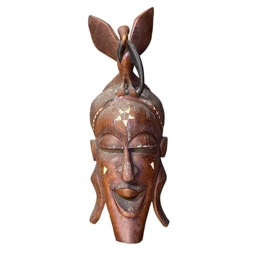 44 - A large African carved mask. Inlaid with bone, height 93cm together with another African carved mask... 