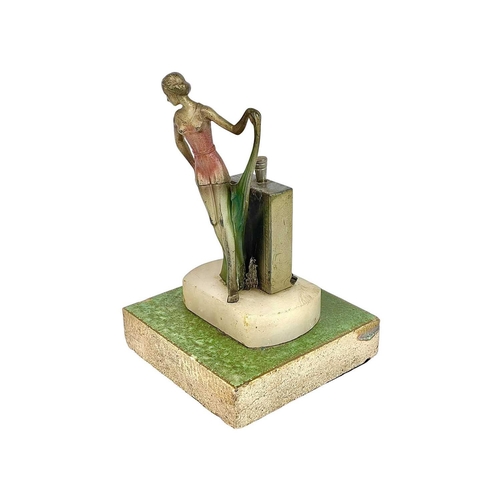 97 - An Art Deco spelter strike table lighter. Modelled as a fashionable lady, with a coloured dress and ... 