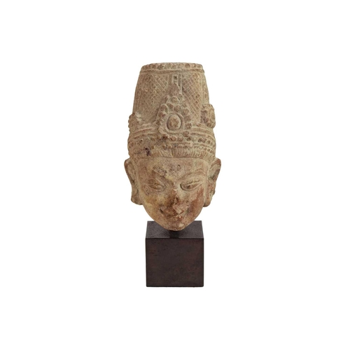 1058 - An Indian red sandstone head of a deity. 16th/17th century, height 18cm, overall height including st... 