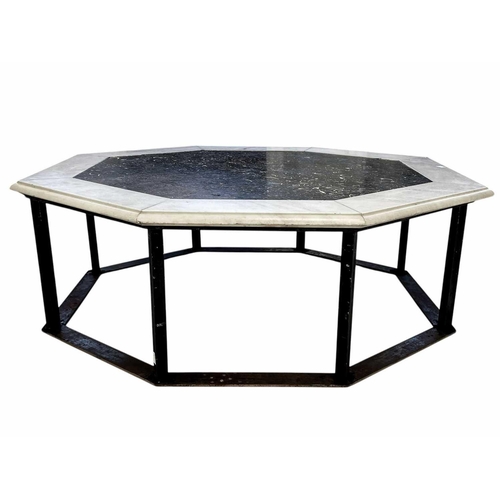 1091 - An octagonal polished fossil bed coffee table. 20th century, within white marble borders, on a wroug... 