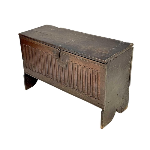 1142 - A 17th century oak plank coffer. The front panel with carved nulling, on shaped end supports, height... 