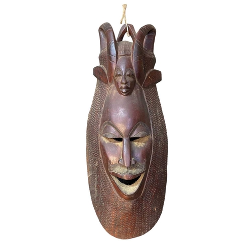 164 - A large African carved mask. Height 67cm together with another larger African mask. (2)