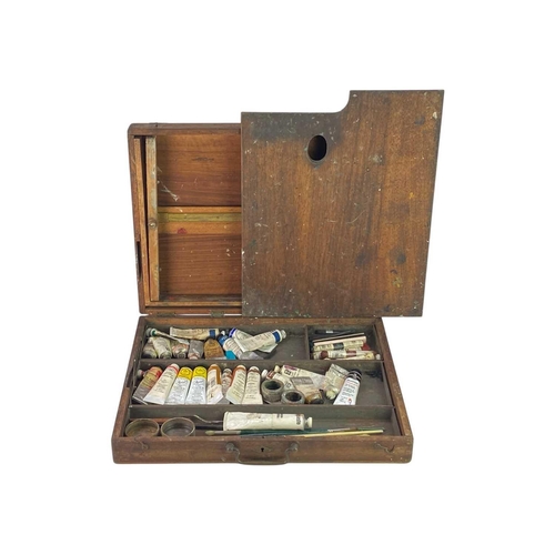 66 - A hardwood Artist's box. Mid 20th century, the hinged cover incorporating an easel, with palette and... 