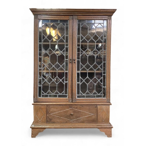 703 - An oak bookcase With adjustable shelves behind leaded doors and with a lower compartment with fall f... 