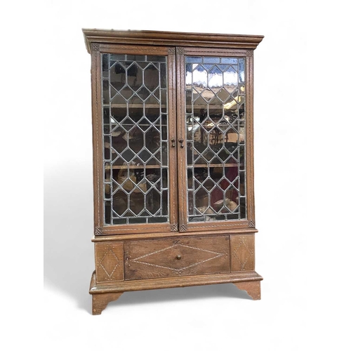 703 - An oak bookcase With adjustable shelves behind leaded doors and with a lower compartment with fall f... 