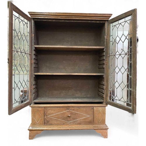 703 - An oak bookcase With adjustable shelves behind leaded doors and with a lower compartment with fall f... 