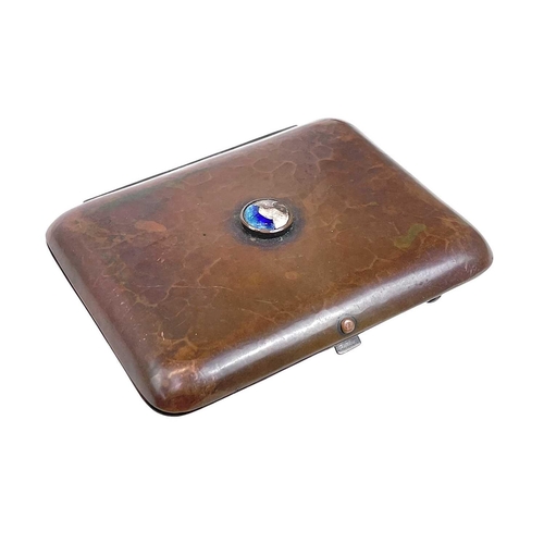 80 - A Newlyn copper and enamel cigarette case. With a planished finish and central blue enamel boss, sta... 