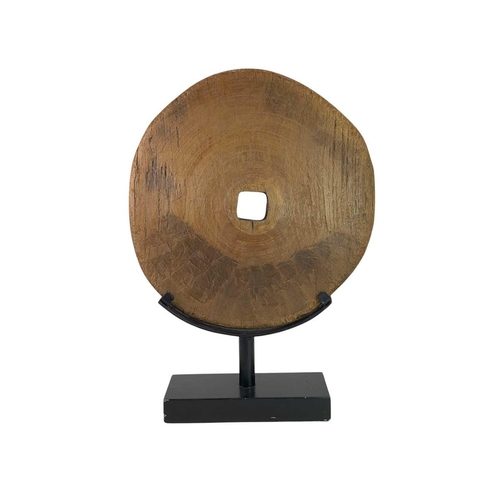 9 - An Eastern hardwood wheel. Mounted as a disc form sculpture, diameter 44cm, overall height 63cm.