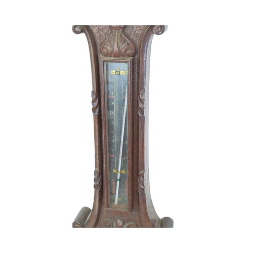 152 - A Negretti & Zambra carved oak aneroid barometer. In a substantial case, the silvered dial numbered ... 