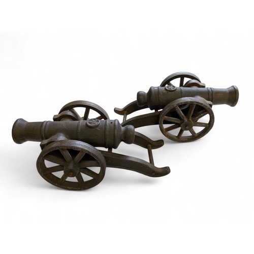 162 - A pair of heavy cast iron models of cannon. Each with a wheeled carriage, length 33cm, together with... 