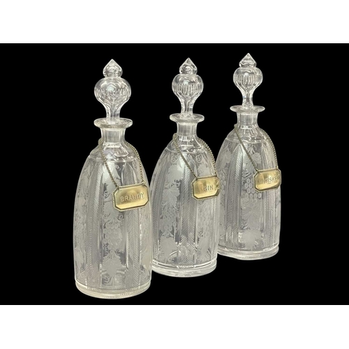 185 - A set of three Victorian engraved glass decanters and stoppers. With plated labels, height 37cm, tog... 