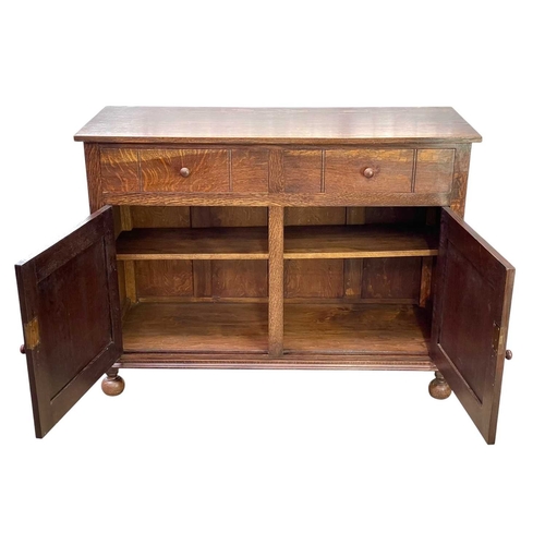 241 - A Heal's oak sideboard. Fitted with two drawers above a pair of cupboard doors, on ball feet, inset ... 