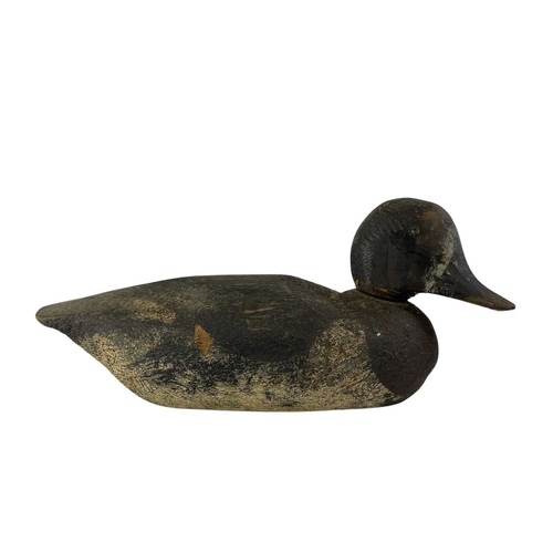 307 - An American carved pine duck decoy. Early 20th century, with a broad painted body, length 31cm, toge... 