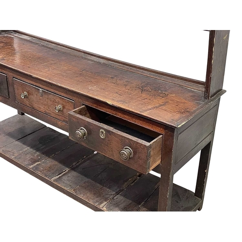 310 - A George III oak dresser and rack. Fitted two shelves above three drawers and with a pot board below... 