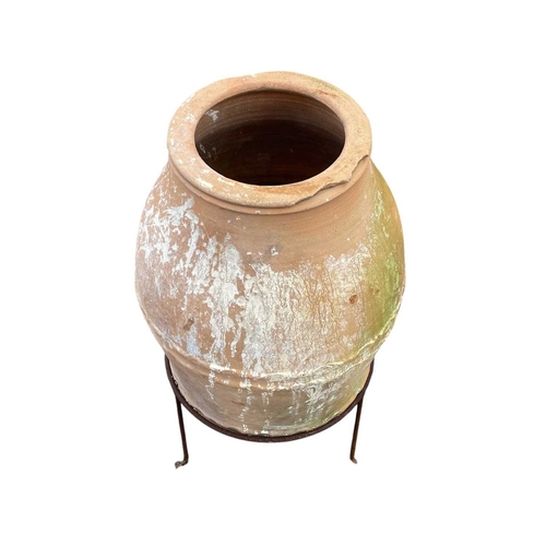 334 - A terracotta olive jar on a stand. With banded decoration, height 80cm, width 34cm.