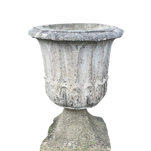 357 - A pair of reconstituted stone urns on matched swept bases. Height 54cm.