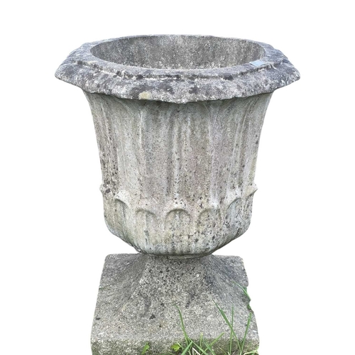 357 - A pair of reconstituted stone urns on matched swept bases. Height 54cm.