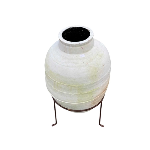 359 - An olive jar on a stand. Terracotta, painted white externally and black internally, height 75cm incl... 