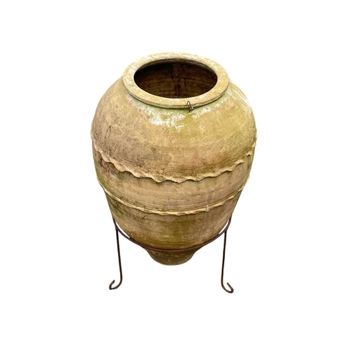 360 - A terracotta olive jar on a stand. With banded decoration, height 75cm, depth 42cm.