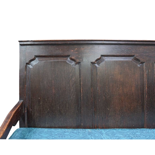 444 - An oak settle with a quadruple fielded panel back. On cabriole front legs, with a loose seat cushion... 