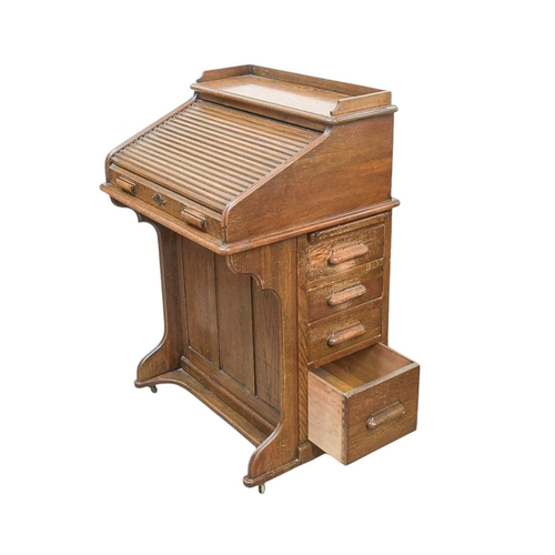 461 - An oak narrow roll top desk. Circa 1920, with a tambour top and fitted with four side drawers, Harro... 