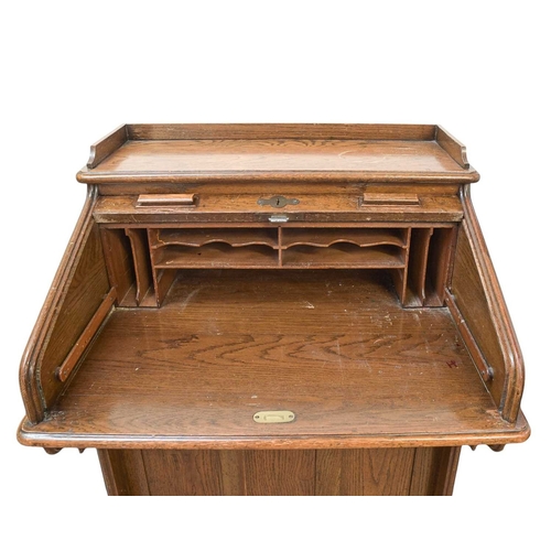 461 - An oak narrow roll top desk. Circa 1920, with a tambour top and fitted with four side drawers, Harro... 