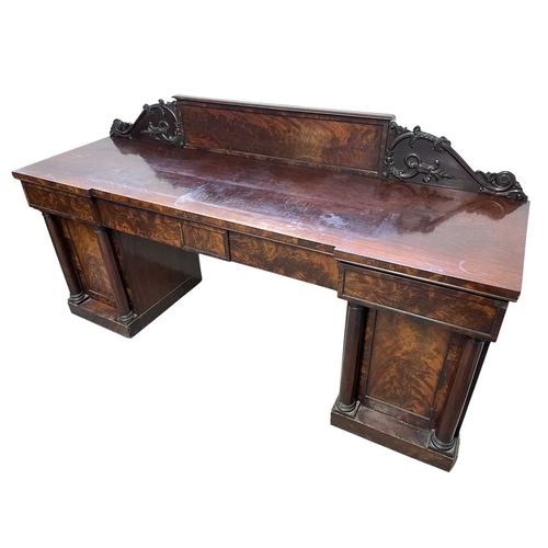 488 - A William IV figured mahogany twin pedestal sideboard. The raised back with a central tablet flanked... 