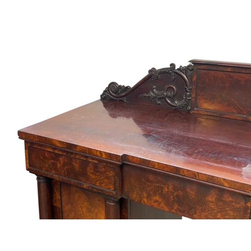 488 - A William IV figured mahogany twin pedestal sideboard. The raised back with a central tablet flanked... 