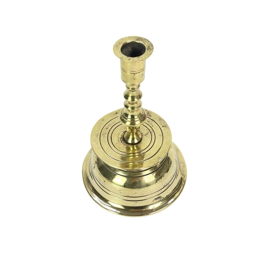 51 - A German Brass Nuremberg candlestick. Late 17th century, with a baluster turned stem above a broad d... 