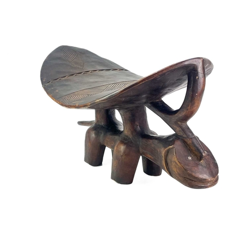 57 - An African hardwood zoomorphic stool. With a carved dished top, and shell inlaid eyes, height 29cm, ... 