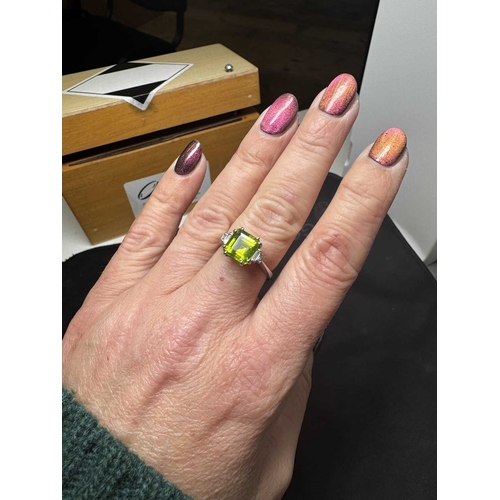 100 - A square emerald-cut peridot and diamond 18k white gold ring. The vivid green peridot is 7mm x 7mm a... 