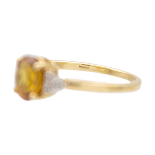 120 - A 9k gold sphene (titanite) and diamond ring. The oval mixed-cut golden sphene is 8mm x 6mm, set wit... 