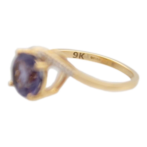 125 - A 9k gold blueberry quartz and diamond crossover ring. A purplish blue round mixed-cut quartz is 8mm... 