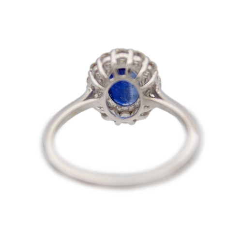 133 - An 18K white gold oval blue kyanite and diamond halo ring. Kyanite, 1.77ct, is surrounded by fourtee... 