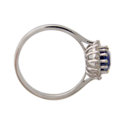 133 - An 18K white gold oval blue kyanite and diamond halo ring. Kyanite, 1.77ct, is surrounded by fourtee... 