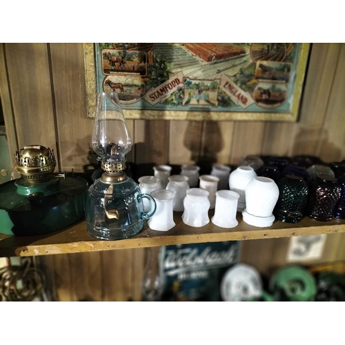 117 - ± Clemence's Ironmongers Glass lamp shades and oil lamp chimneys The top shelf contents to include m... 