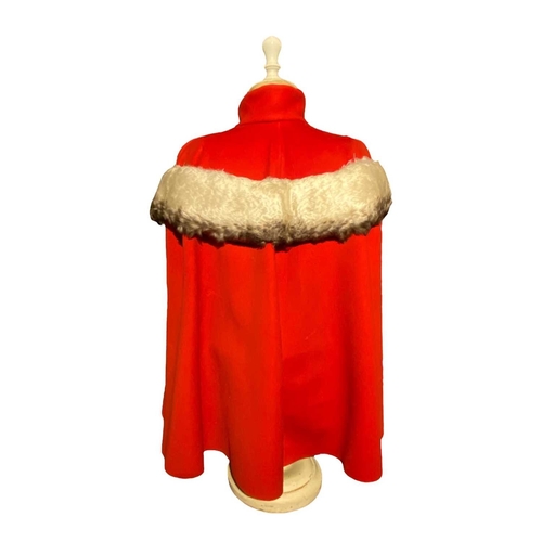 595 - ± K Fillingham Milliners Wool cape & mannequin In left hand shop window display, a red wool felt cap... 